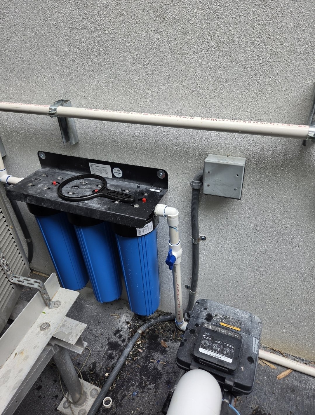 Installed three-stage Big Blue filter system beside an outdoor air-conditioning unit